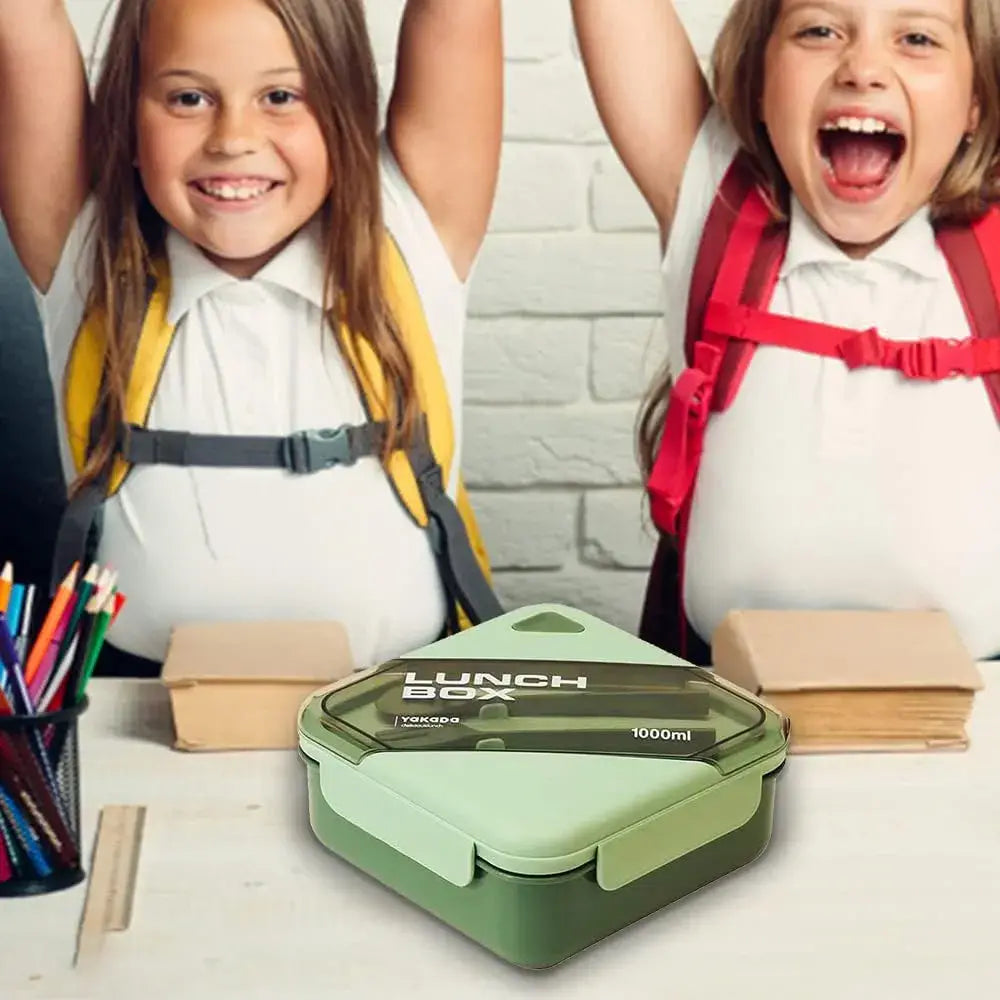 Two children with backpacks sitting at a table with a green lunch box in front of them.