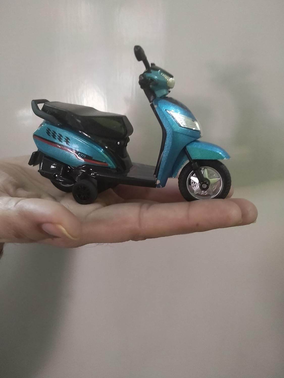 Blue pull back scooty toy for kids held on a hand showing detailed design and small size