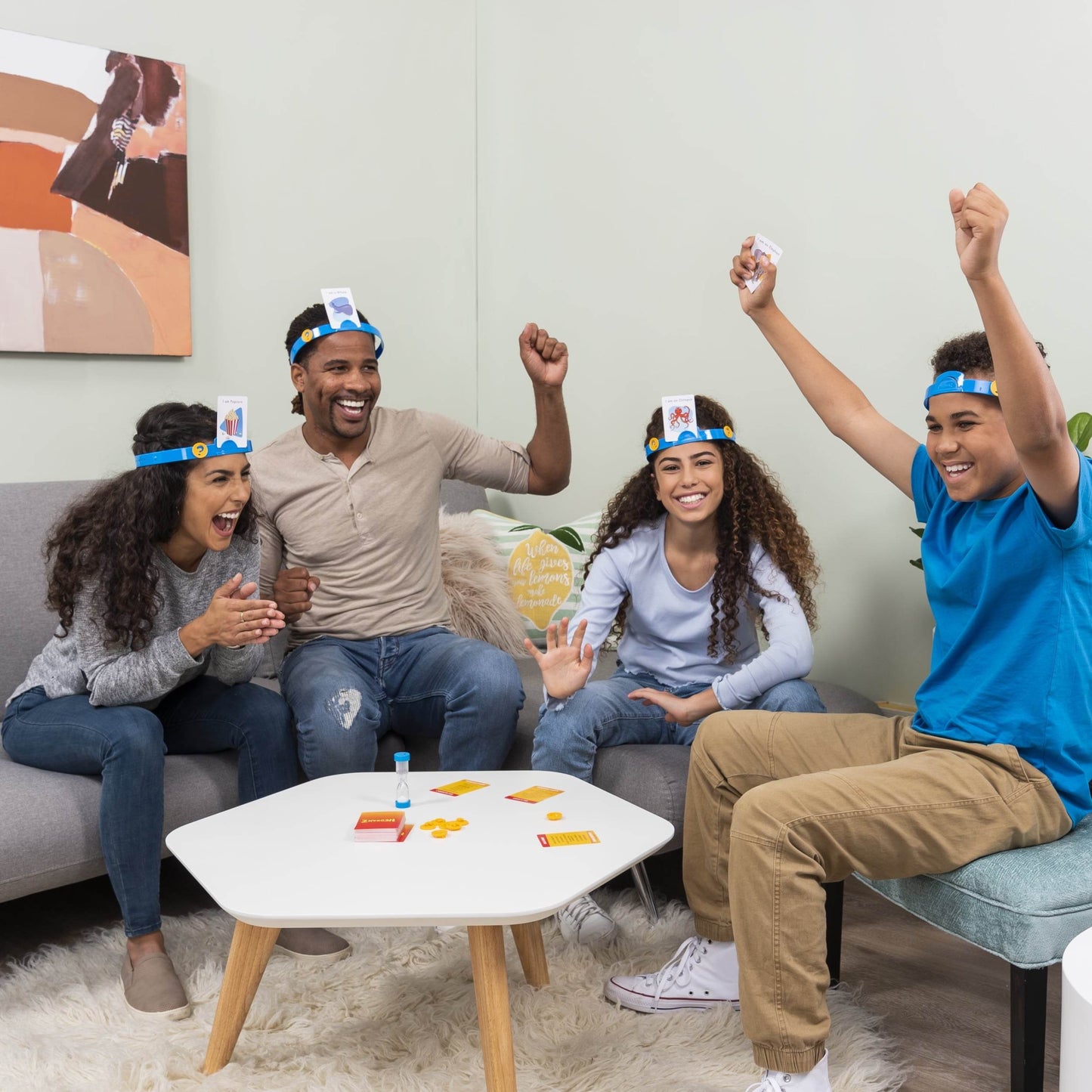 Family playing Hedbanz family game India by Hasbro wearing headbands and holding cards indoors