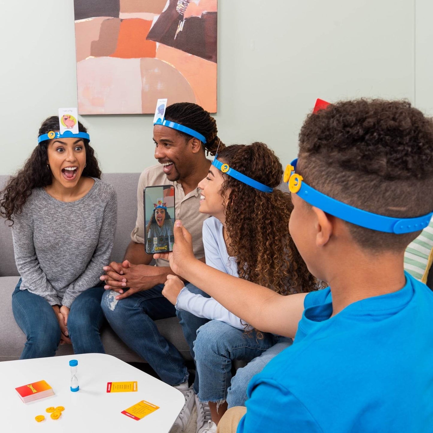 Family playing Hedbanz family game India by Hasbro with blue headbands and cards indoors