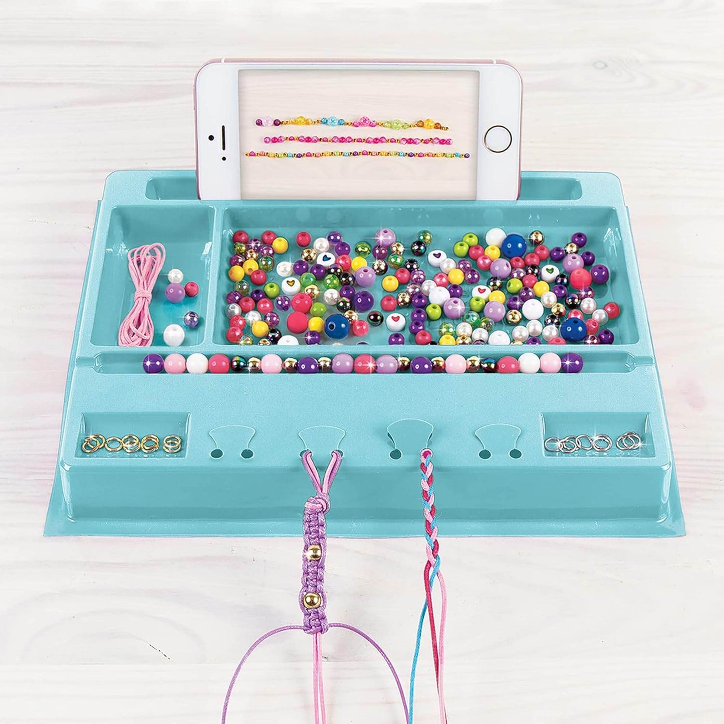 Make your own jewelry set with colorful beads and strings organized on a blue tray with phone holder