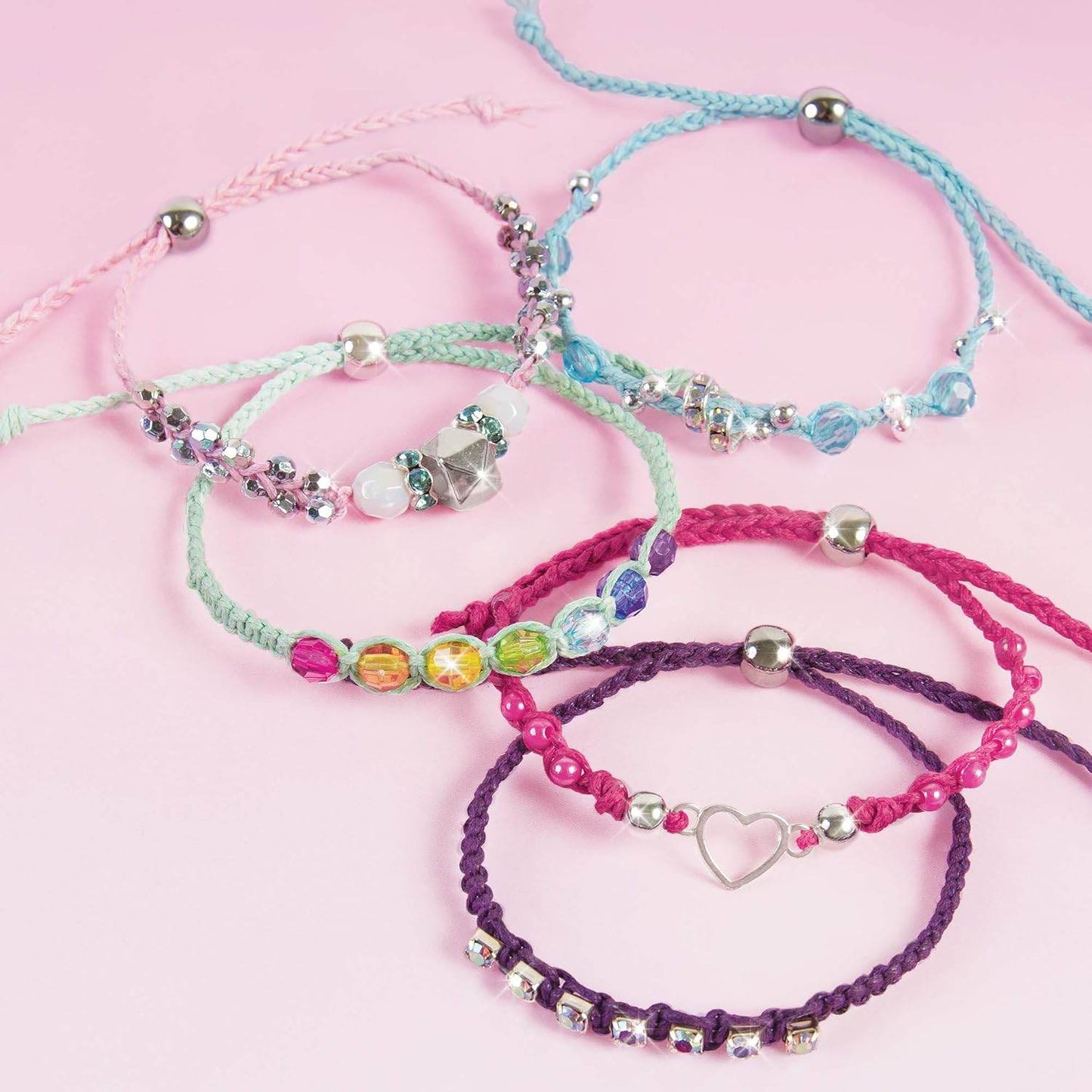 Colorful handmade rainbow bling bracelet kit with beads and charms on pink background