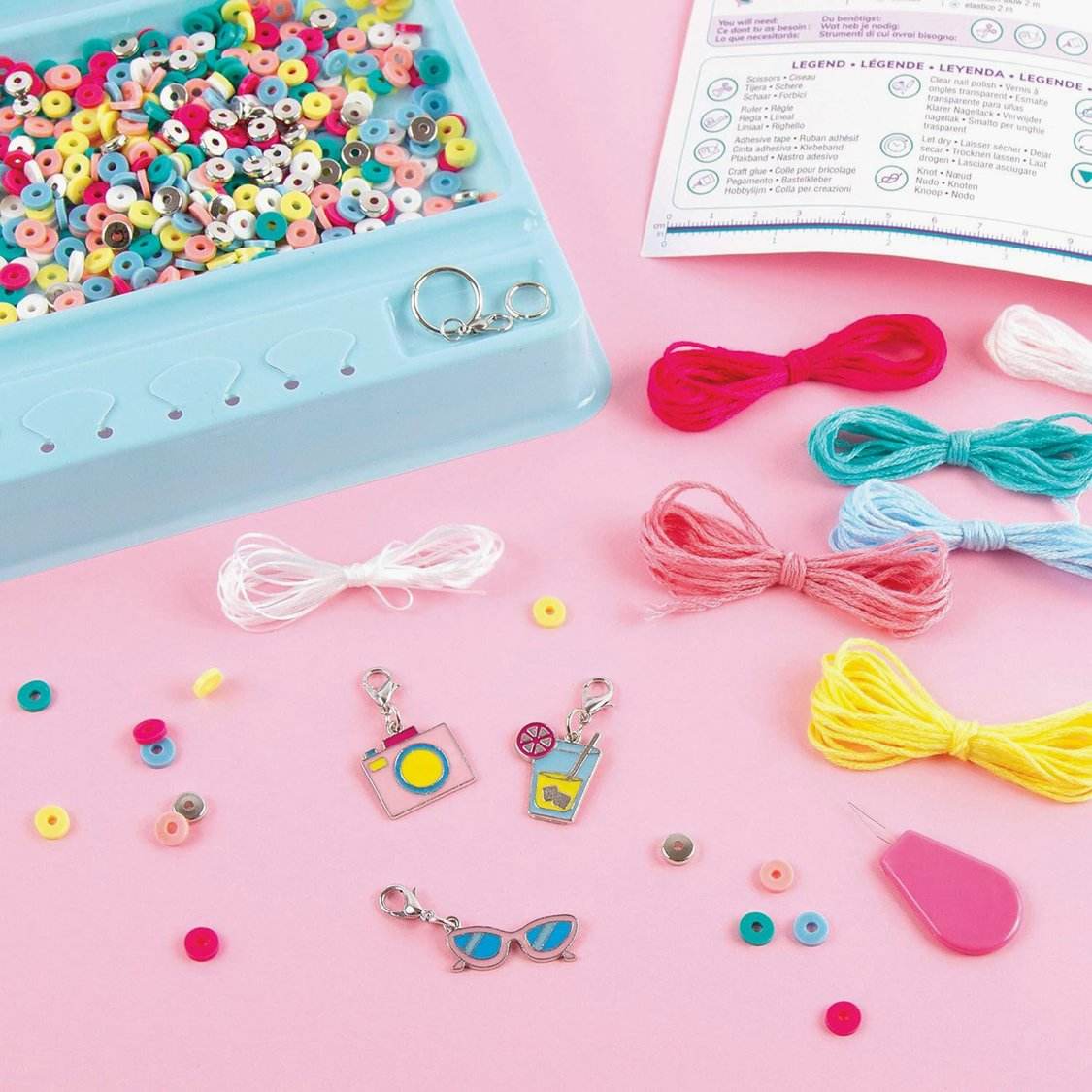 Summer vibes bead bracelet kit with colorful beads, threads, charms, and crafting tools on a pink background