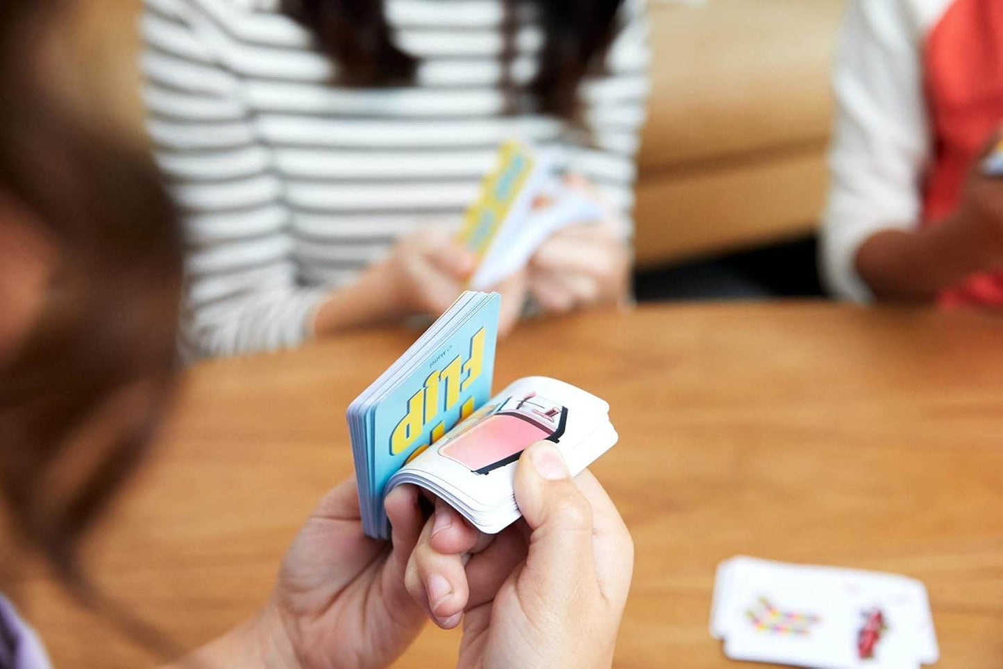 Children playing Pic Flip card game for kids with colorful illustrated cards at a wooden table