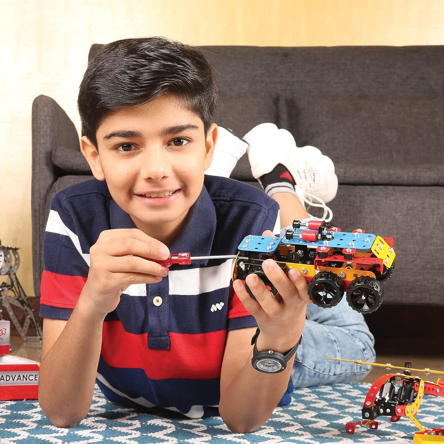 Boy assembling colorful Mechanix Advance STEM toy vehicle with screwdriver indoors