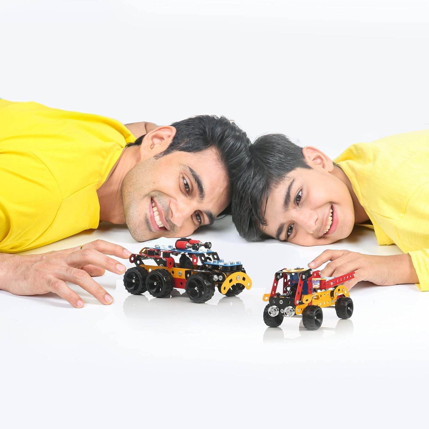 Father and son playing with Mechanix Advance STEM toy model vehicles on a white surface