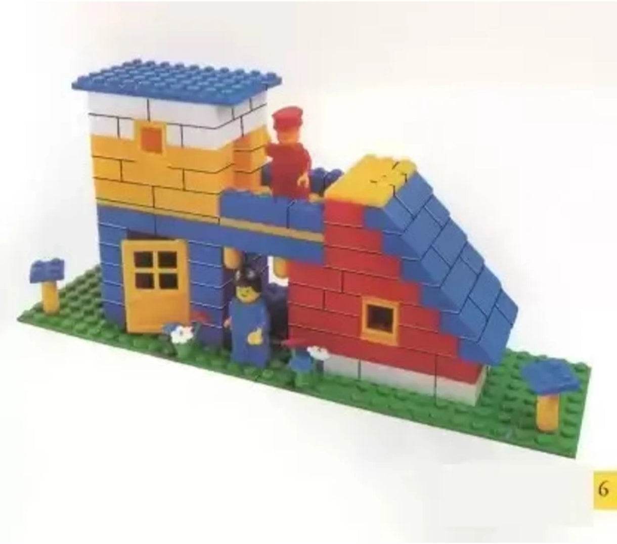 Colorful architect building blocks set assembled into a house with blue roof and figures on green base