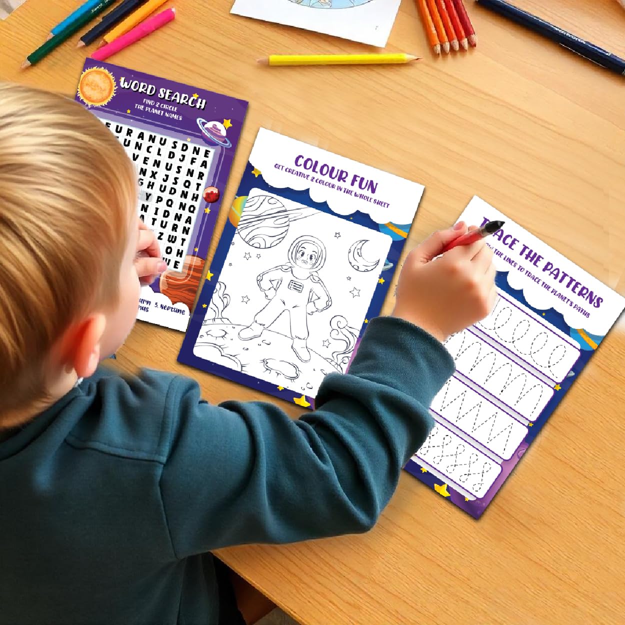 Child engaged in educational activities with coloring books and pencils on a wooden table.