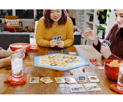 Family enjoying a fun game on board game night with colorful cards and snacks