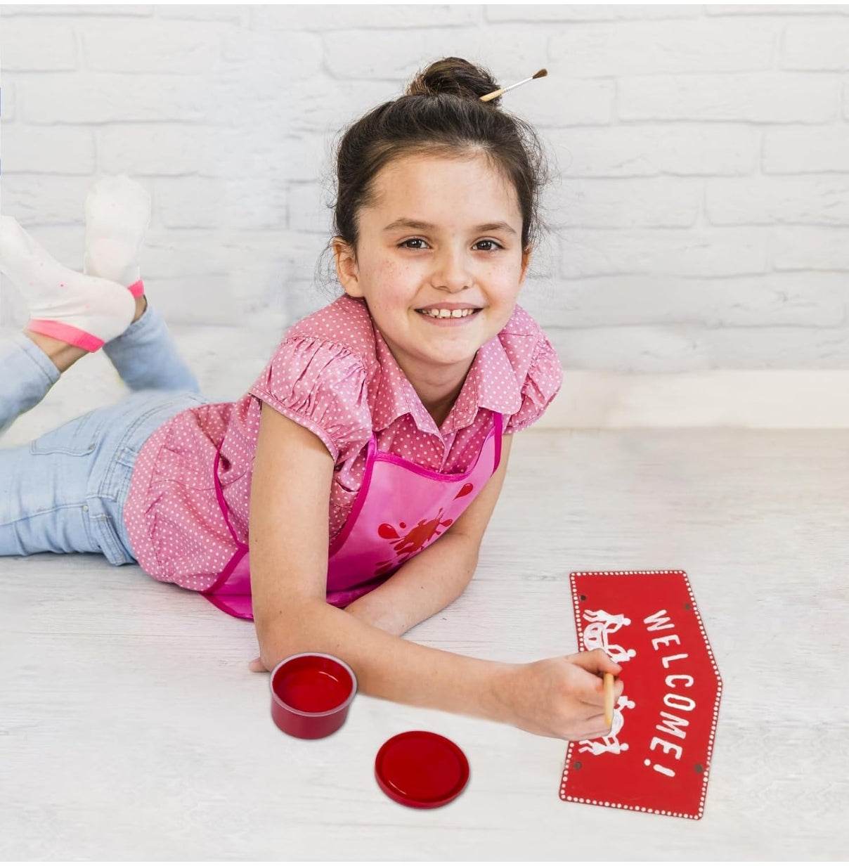 Girl painting a red welcome sign with Warli art designs using Warli art DIY kit for kids
