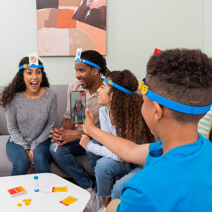Family playing Hedbanz family game India by Hasbro with blue headbands and cards indoors