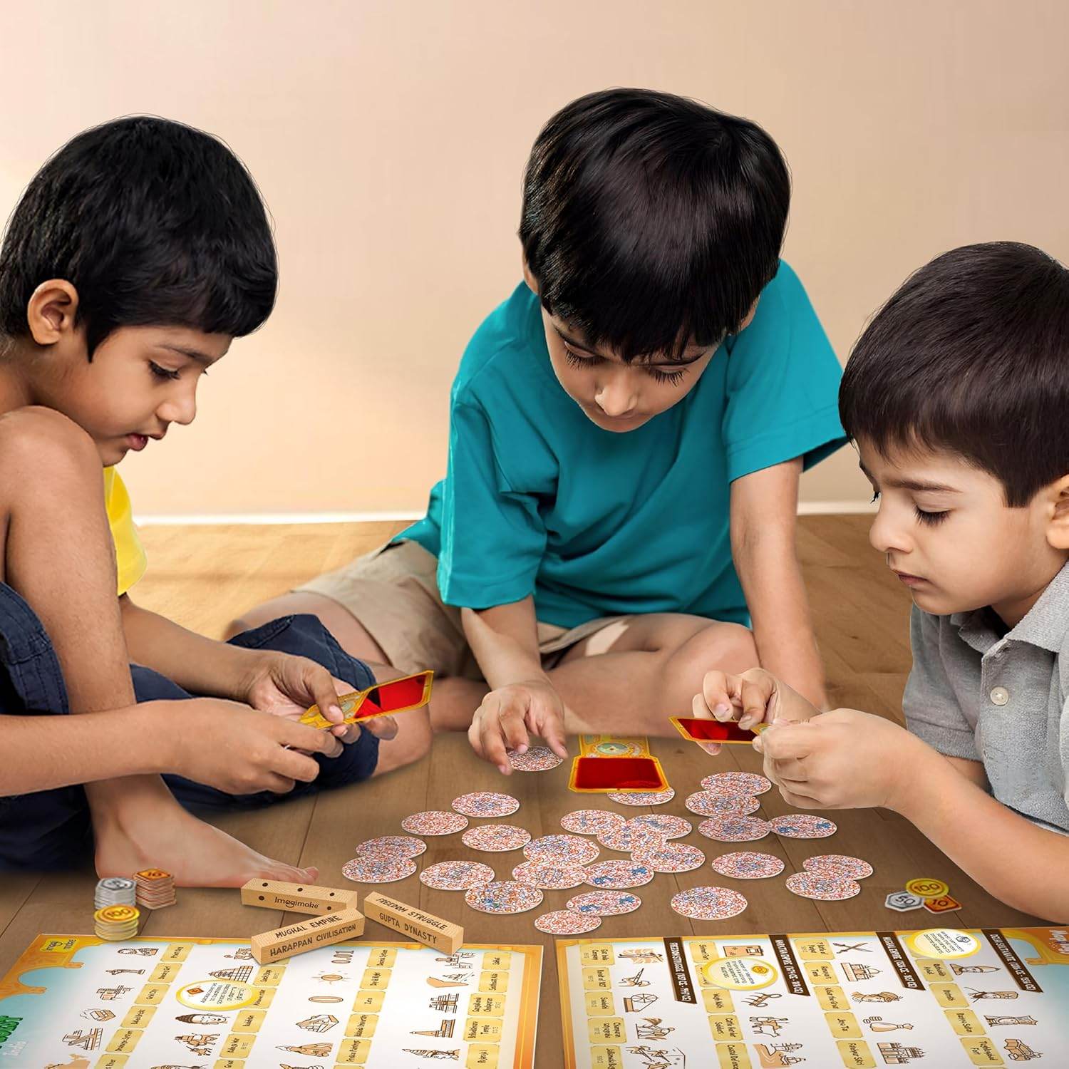 Three children playing Imagimake Mapology History Quest educational game with cards and tokens on wooden floor