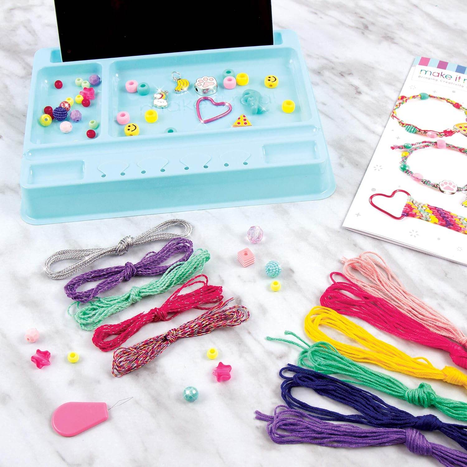 DIY charm bracelet kit for kids with colorful threads beads and charms on a blue organizer tray