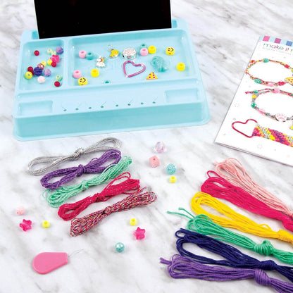 DIY charm bracelet kit for kids with colorful threads beads and charms on a blue organizer tray