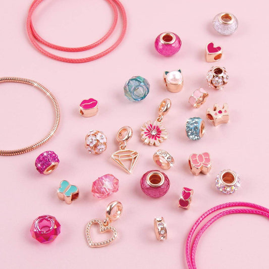 DIY charm bracelet kit for kids with colorful beads and gold-tone charms on pink background