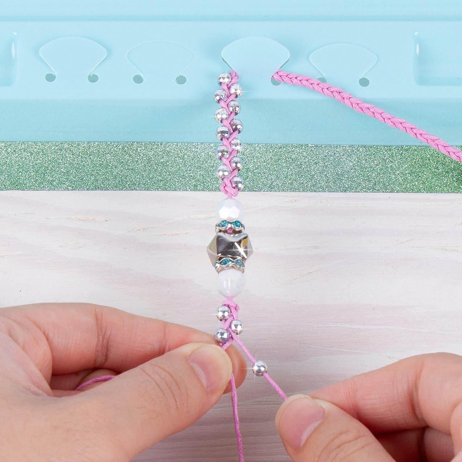 Hands making a pink beaded bracelet using the rainbow bling bracelet kit with beads and threading tool