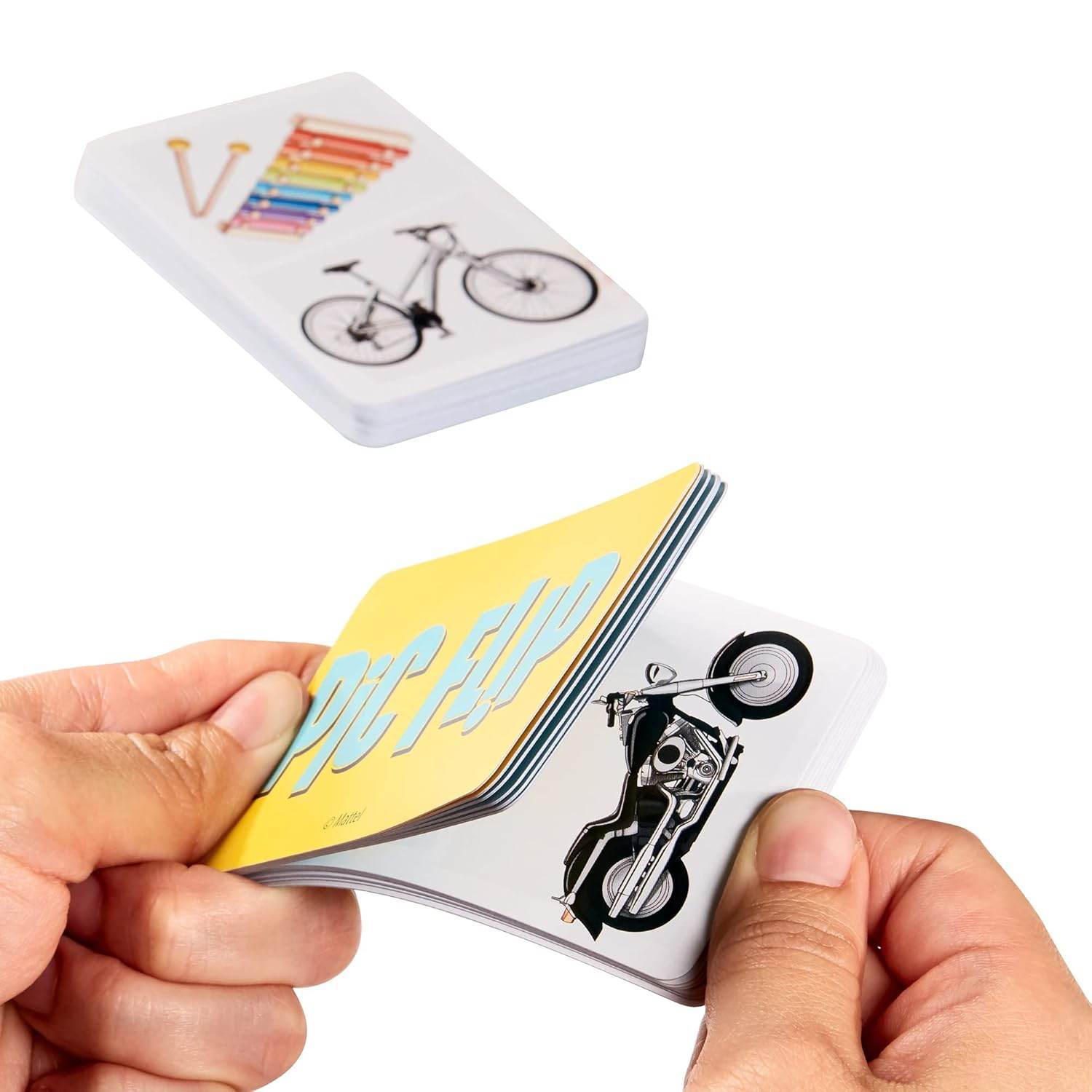 Hands flipping through Pic Flip card game for kids showing colorful images like a motorcycle and bicycle
