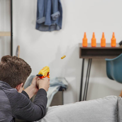 Person aiming and firing a yellow toy gun from the Nerf Alpha Strike set indoors at orange targets